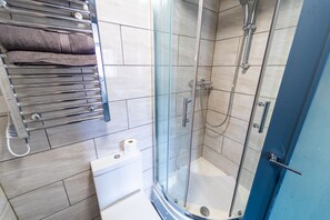A modern bathroom with a glass-enclosed shower, a towel rack, and a toilet.