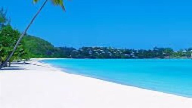 A beach with white sand and clear blue water.