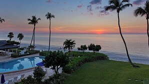 A pool area with lounge chairs and a view of the ocean at sunset. - Villa Bellevue - Beautiful lakefront rental with pool with 3 bedroom & 2 bath (Naples)