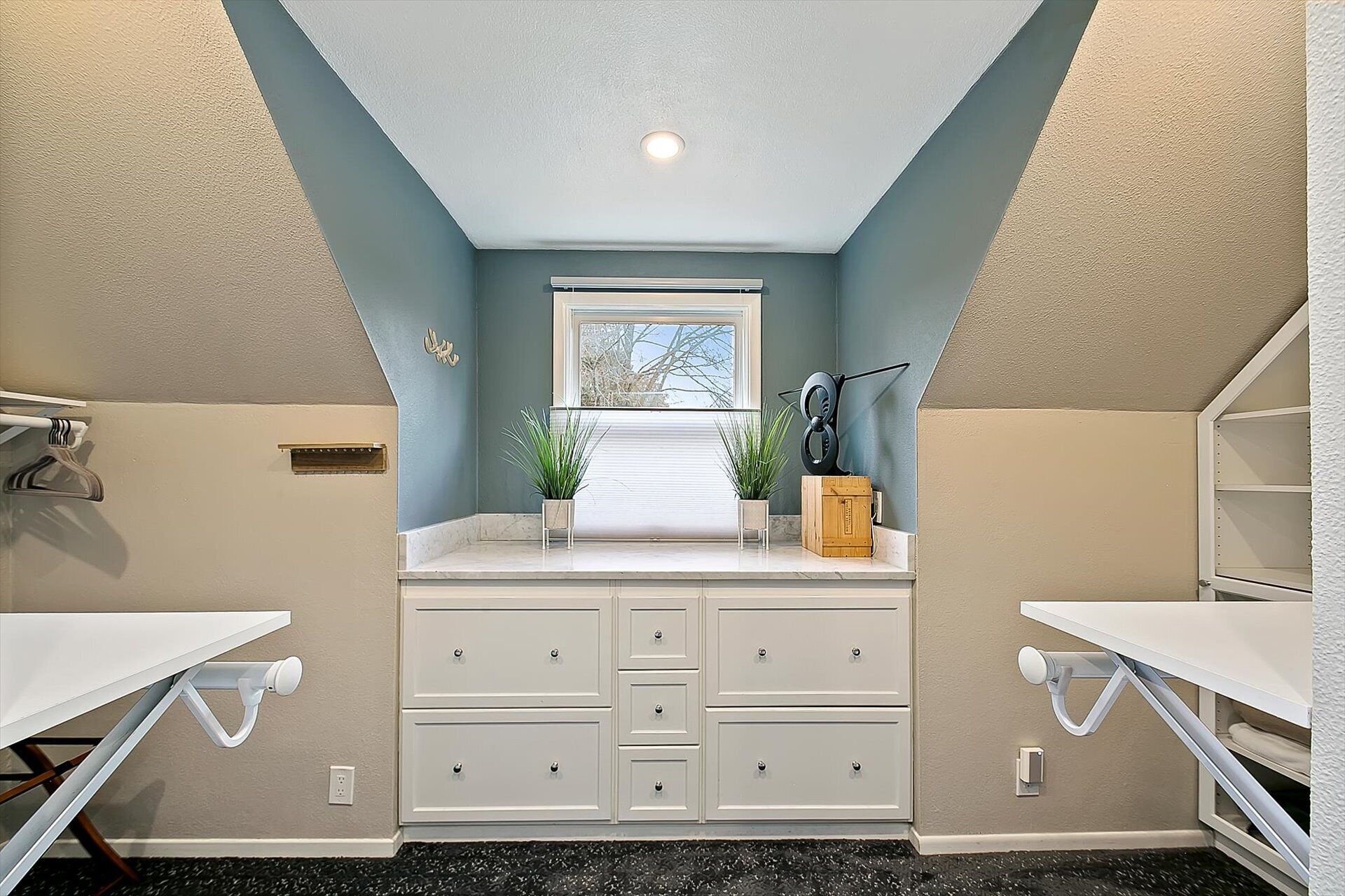 Une chambre à coucher de taille réduite, avec un plafond en pente, une fenêtre, un bureau et une commode.
