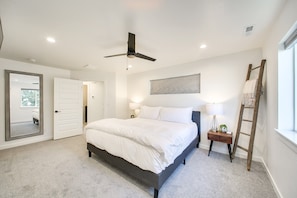 A bedroom with a bed, a ceiling fan, a nightstand, a lamp, a ladder, and a window. - Crossroads Retreat (Boise)