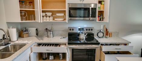 Une cuisine compacte équipée d’un four à micro-ondes, d’une cuisinière, d’un four et d’armoires encastrées.
