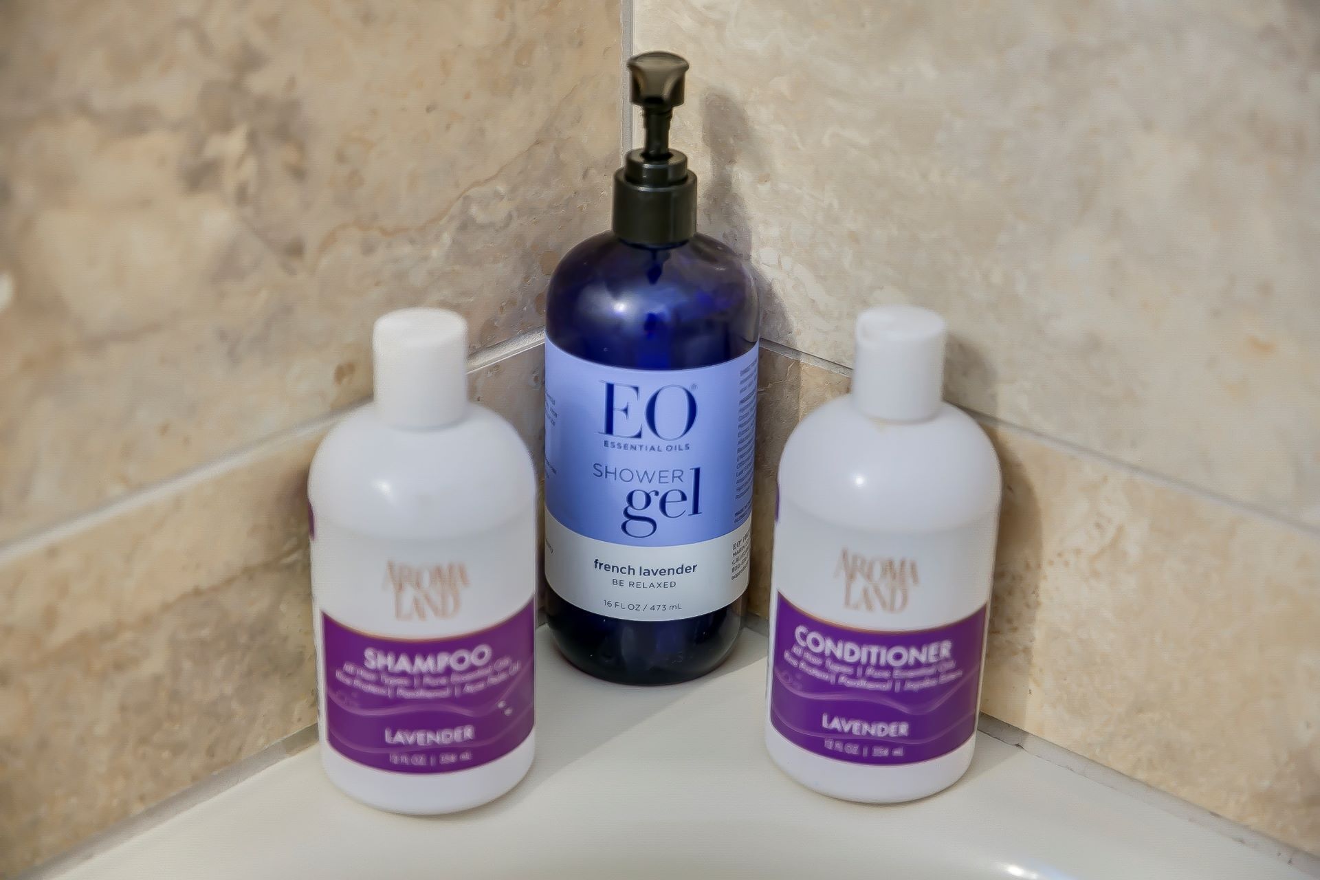 Trois flacons de produits de la marque EO Essential Oils sont posés sur le comptoir d’une salle de bain.