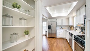 A modern kitchen with white cabinetry, a stainless steel refrigerator, and a wooden floor. - Elm Grove Elegance (Boise)
