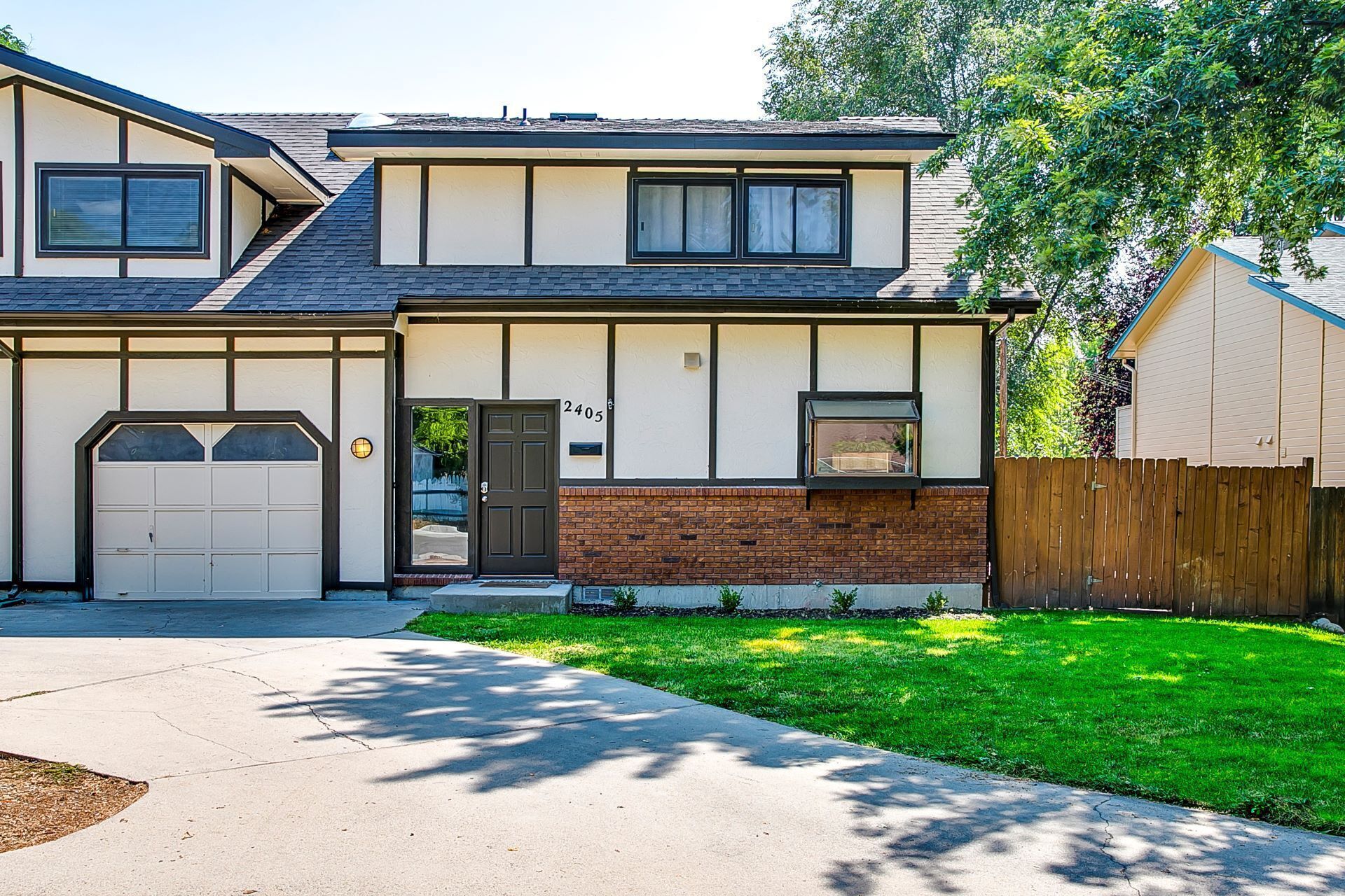 A two-story house with a garage, a brick section on the ground floor, and a number 2405 on the front door.
