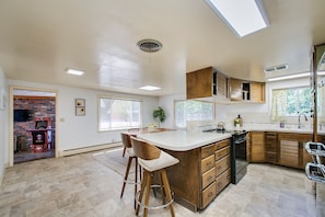 A modern kitchen with a large island, wooden cabinets, and a skylight. - Eagle Rock Base Camp (Boise)