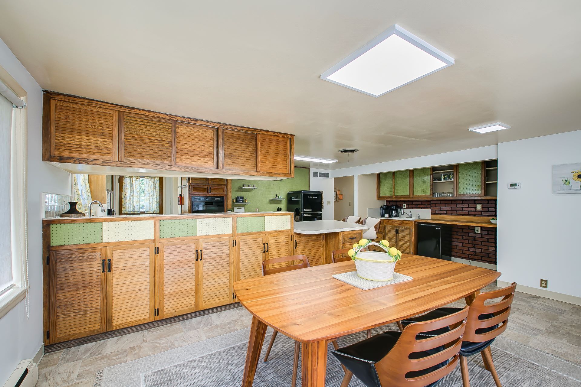 A compact kitchen with wooden cabinets, a dining table, and a refrigerator.