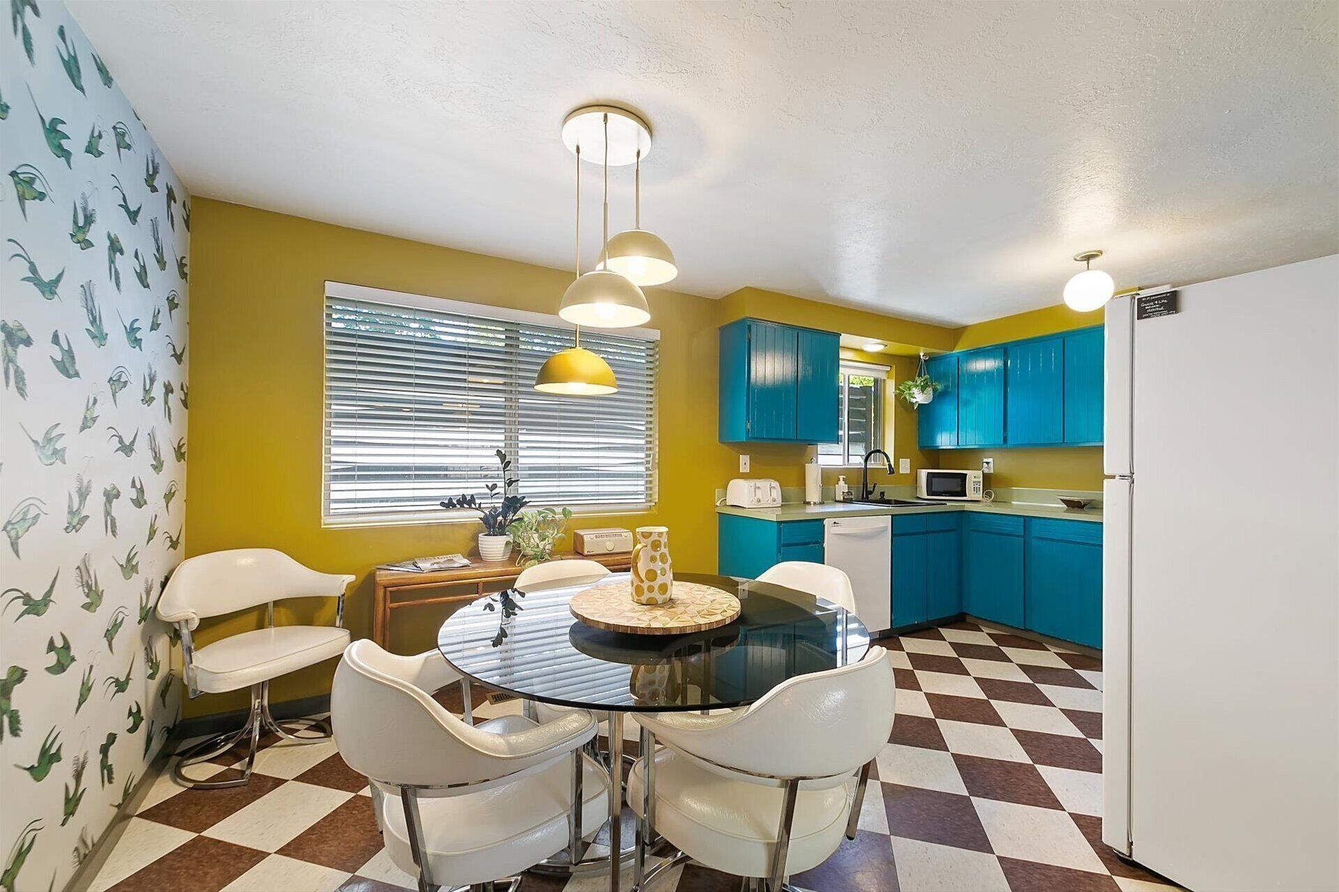 A compact kitchen with blue cabinets, a white refrigerator, and a checkered floor.