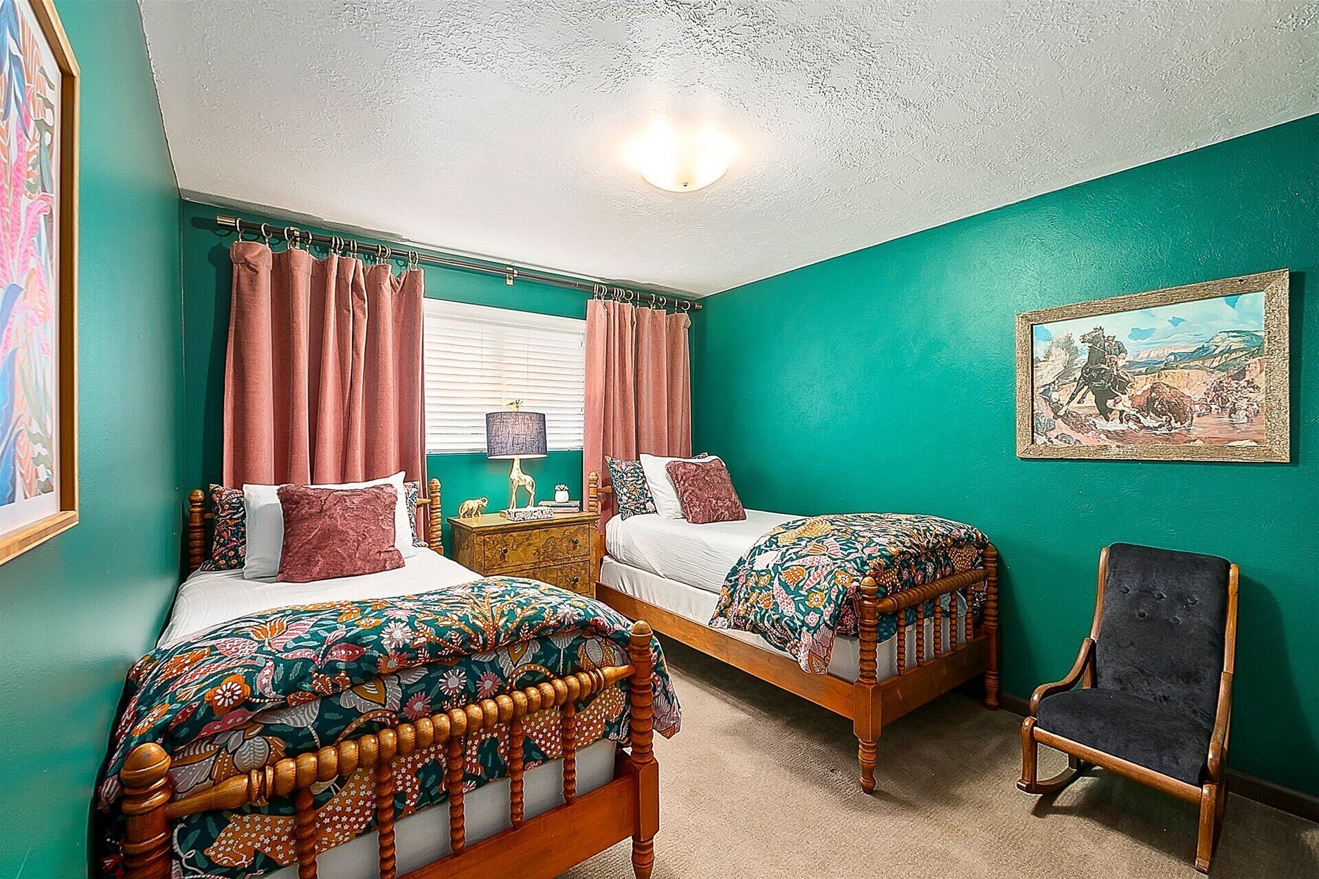 A bedroom with two beds, a nightstand, a chair, and a painting on the wall.