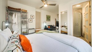 A bedroom with a bed, a wardrobe, a desk, and a shower area. - The Green Spot Studio (Boise)