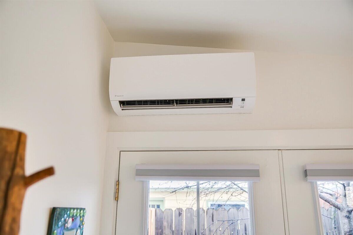 A white air conditioning unit mounted on a wall above a door with a window.