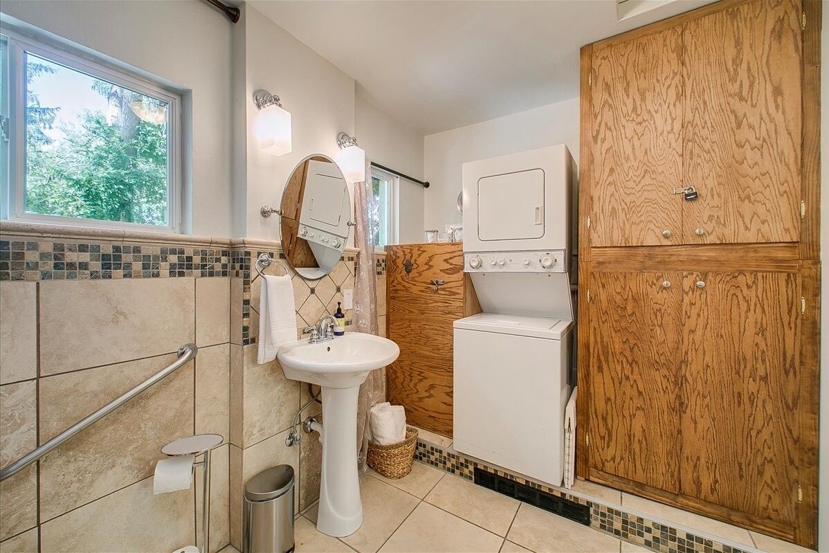 A bathroom with a sink, mirror, towel rack, toilet, and a wooden cabinet.