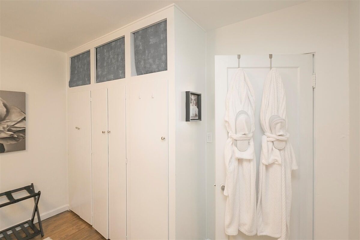 A bathroom with white cabinets, a towel rack with two white towels, and a framed picture on the wall.
