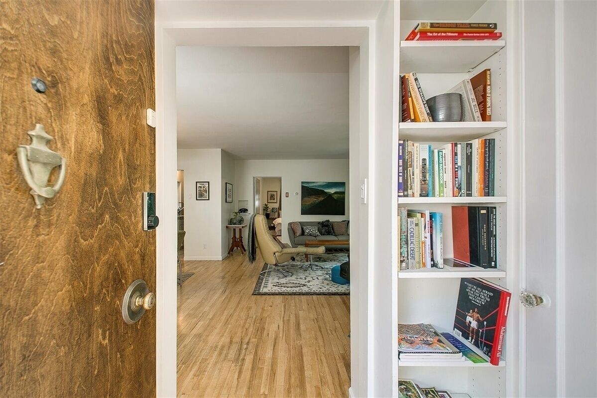A room with a wooden door, a bookshelf, a sofa, and a rug.