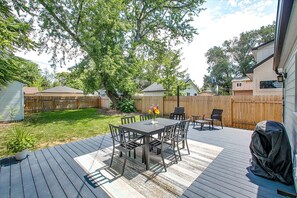 A backyard with a wooden deck, a dining table with chairs, a covered grill, and a wooden fence. - The Valiant Vic (Boise)