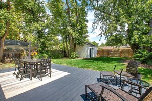 A deck with a table and chairs, surrounded by a wooden fence and lush greenery. - The Valiant Vic (Boise)