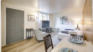 Un espacio habitable compacto con televisor, asientos y una zona de comedor.