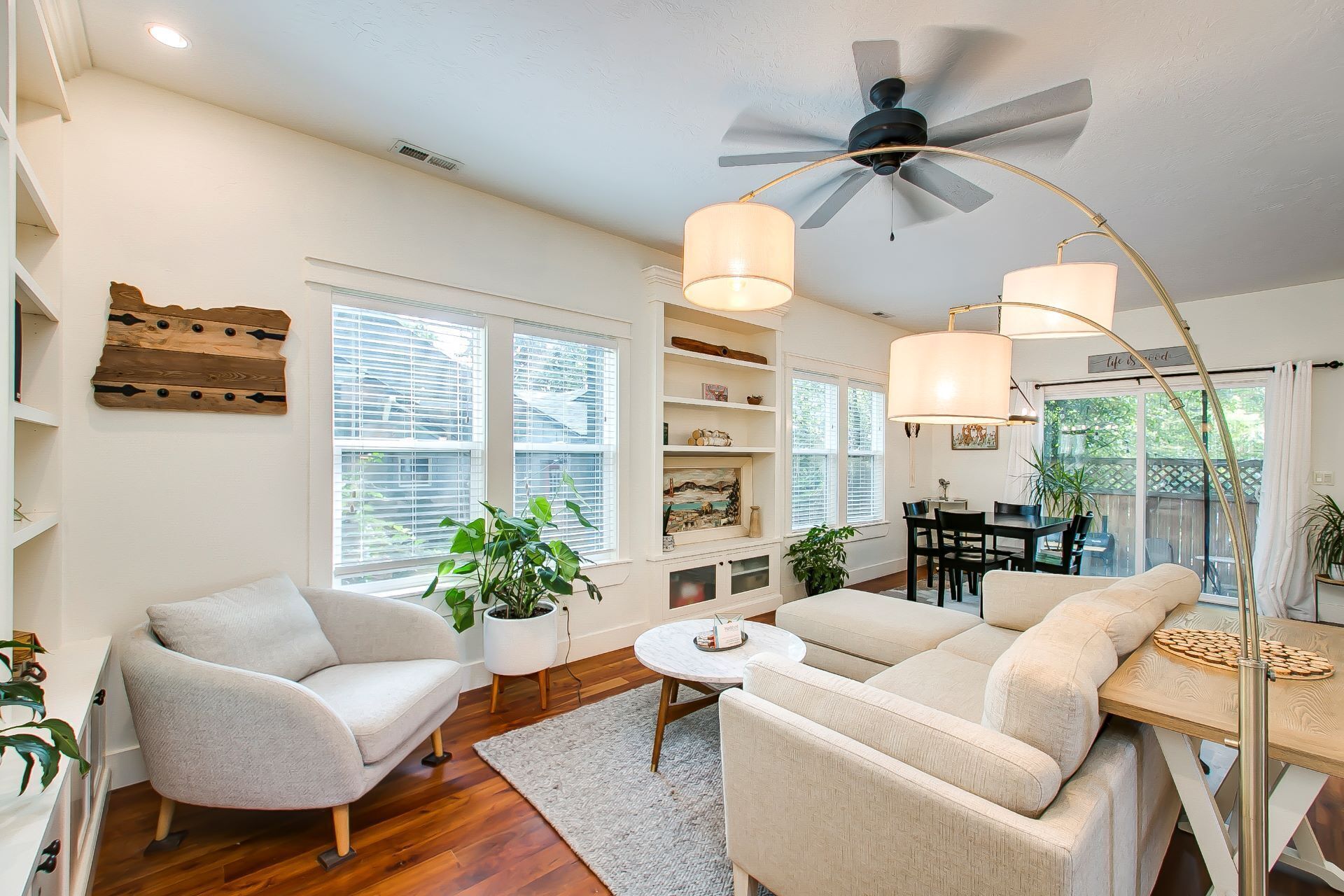 A spacious living room with a ceiling fan, two sofas, a dining table, and a bookshelf.