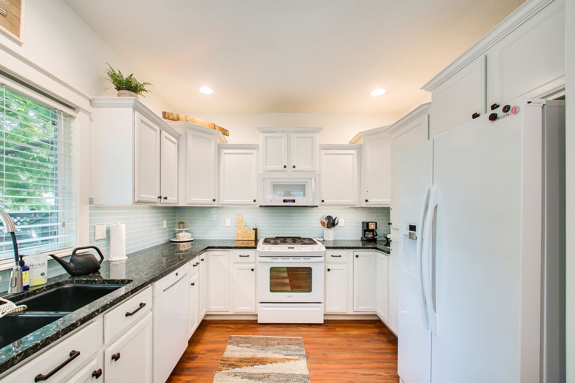 A kitchen with white cabinets, a stove, a microwave, and a refrigerator.