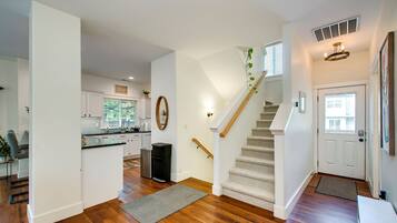 A spacious kitchen with white cabinets, a wooden countertop, and a window with blinds.