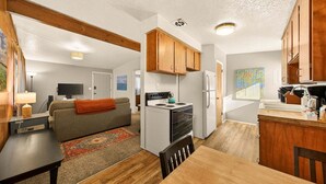 A compact living space with a kitchenette, a sofa, a dining table, and a TV in the background. - Red Ivy #5 (Boise)
