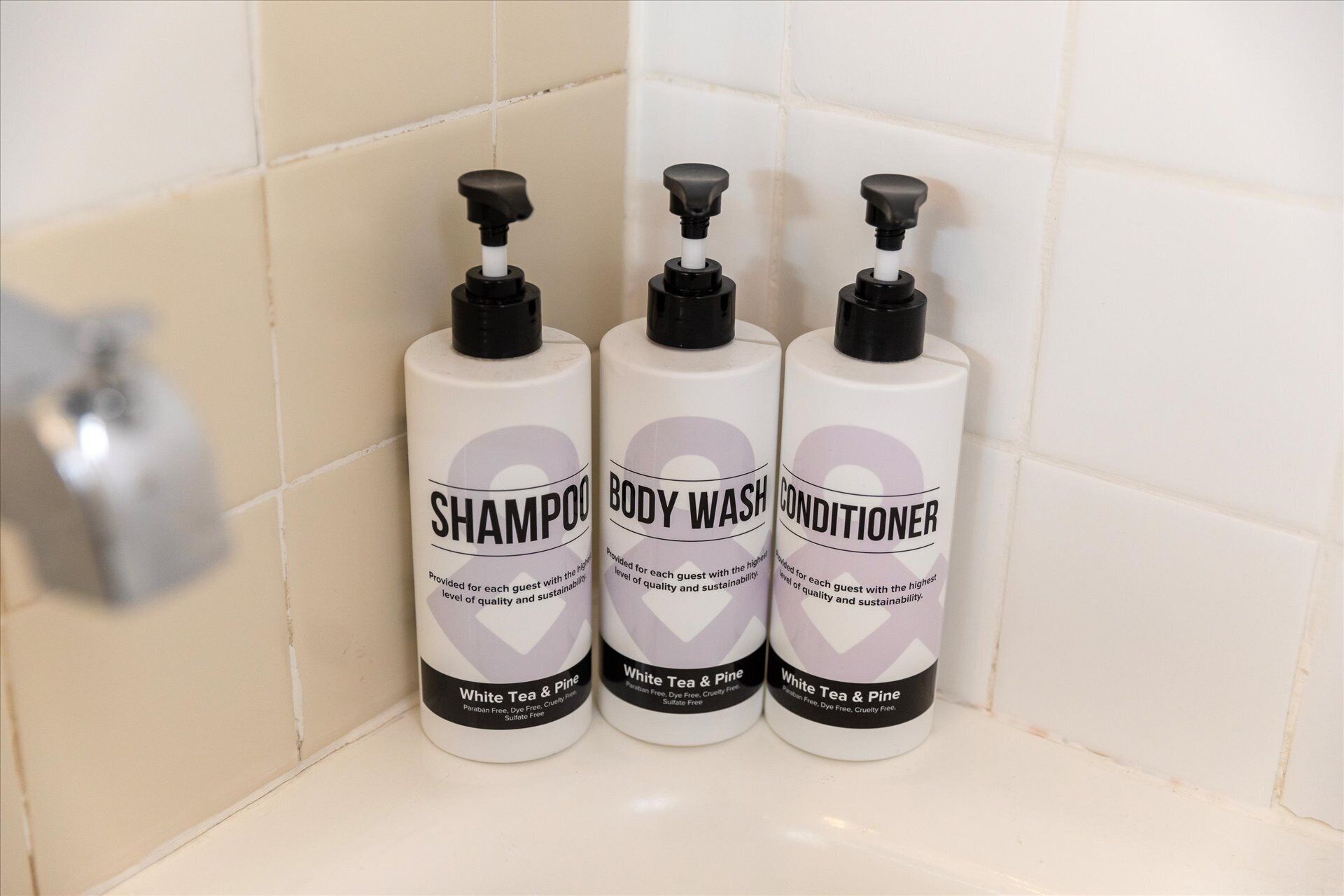 Drie flessen douchegel en conditioner in een badkamer.