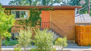 A two-story house with a brick facade, a red door, and a wooden fence. - Red Ivy #5 (Boise)