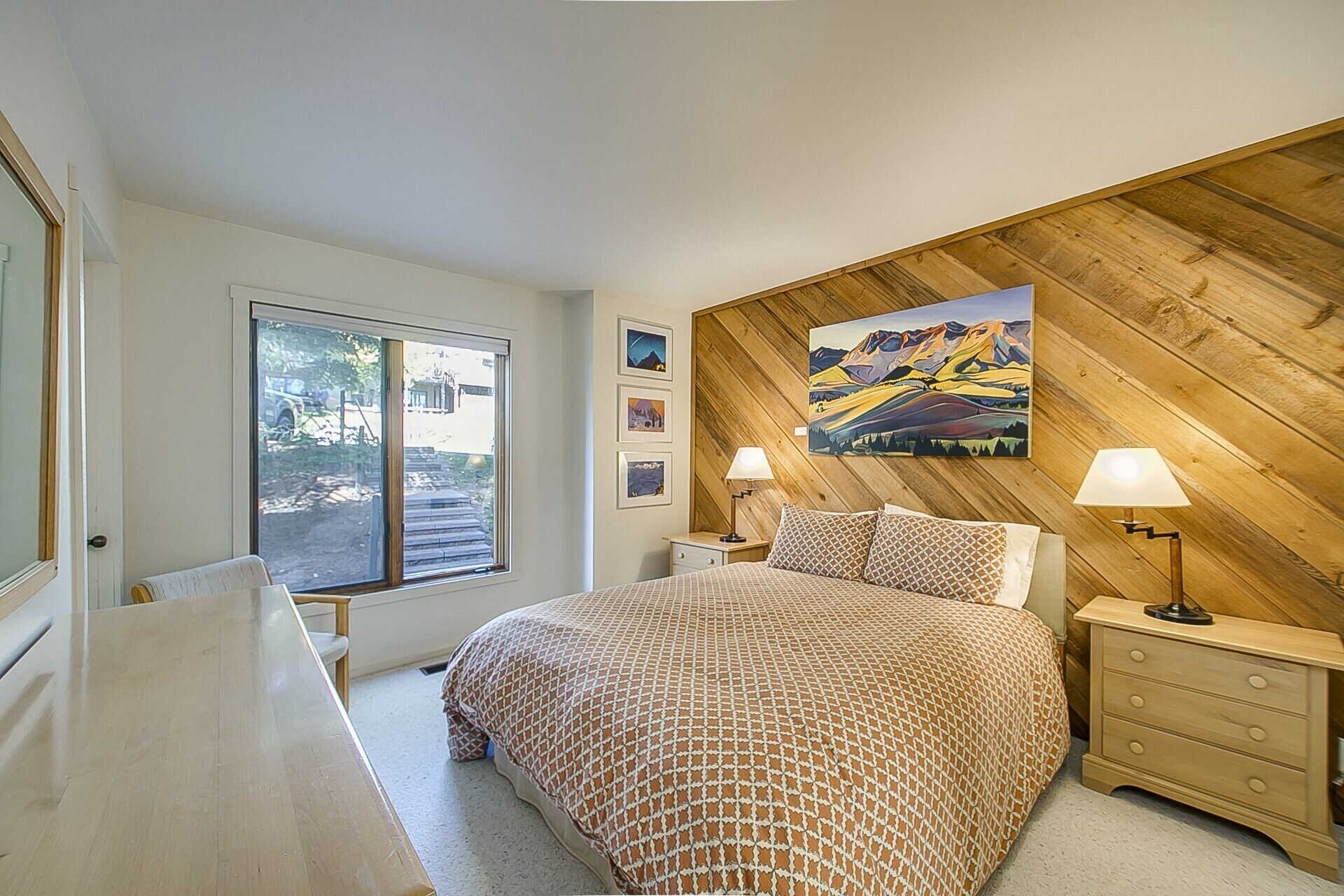 A bedroom with a large bed, wooden panel wall, and a window with a view of the outside.