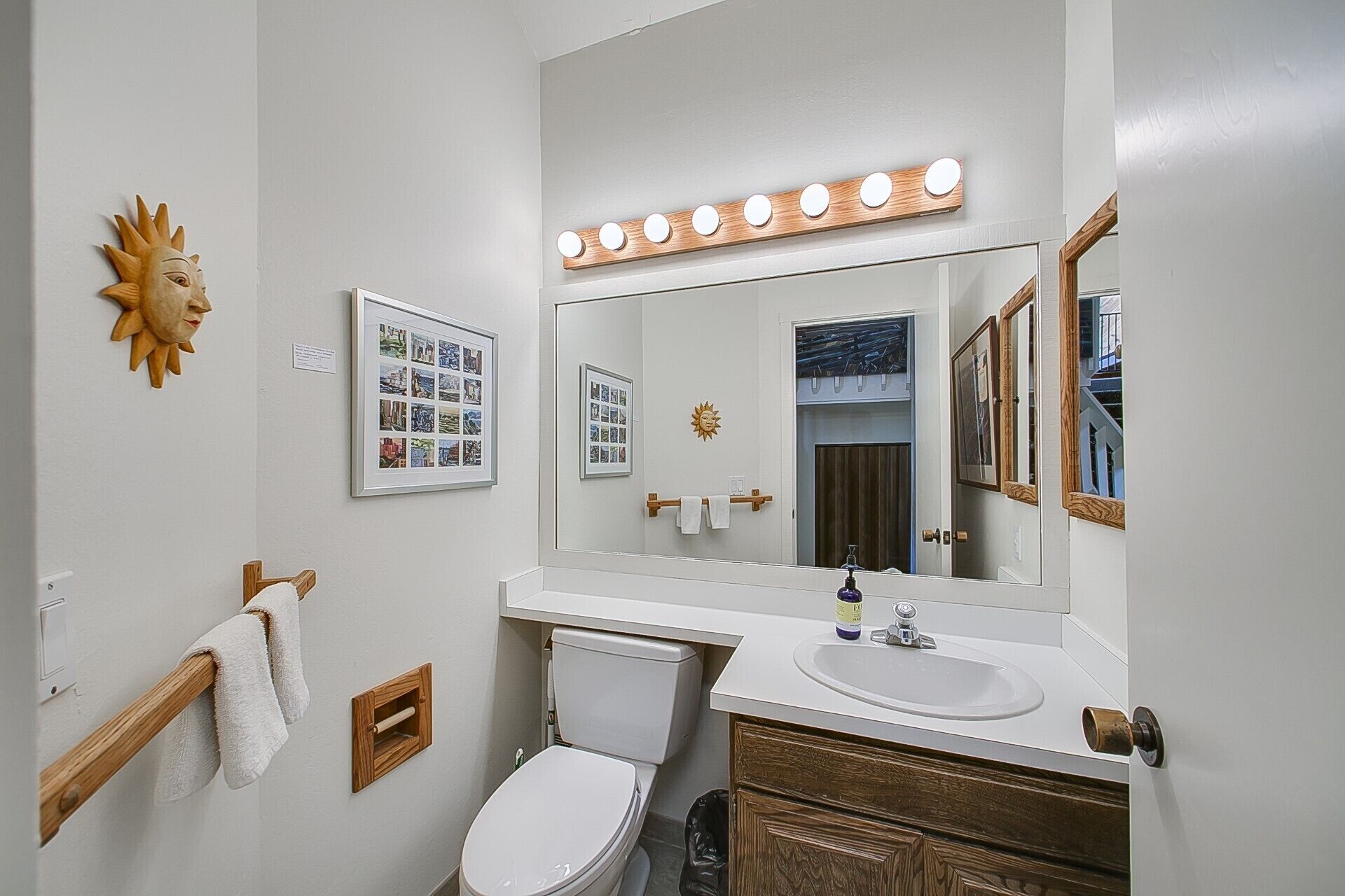 Une salle de bain équipée d’un meuble-lavabo, d’un lavabo, d’un miroir et de toilettes.