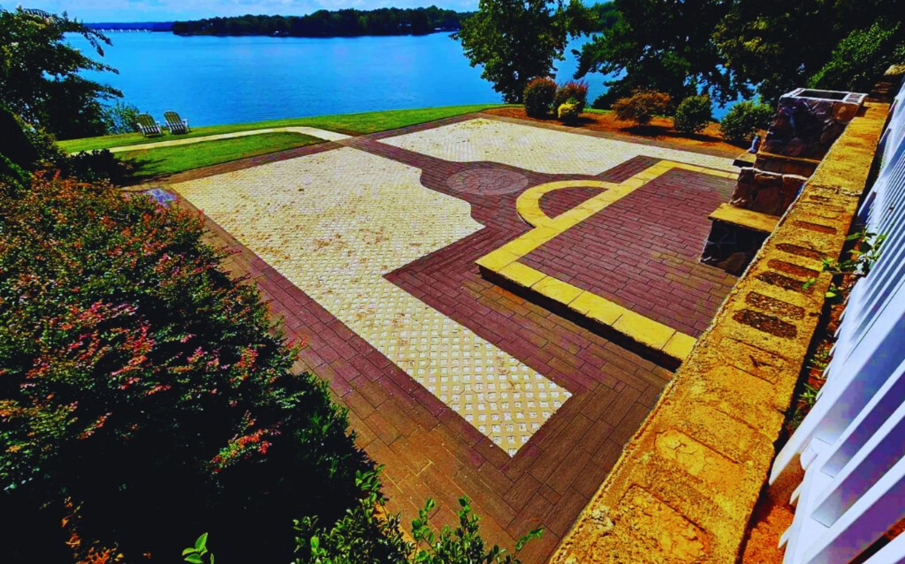 Un área ajardinada con una intersección pavimentada, una masa de agua al fondo y un edificio a la derecha.