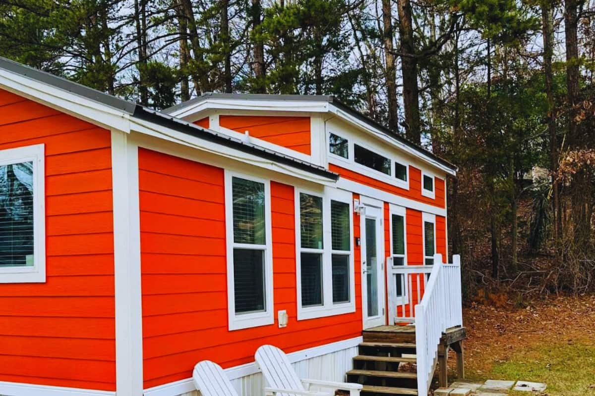 A red and white two-story cabin with a porch and a set of stairs leading to the entrance.
