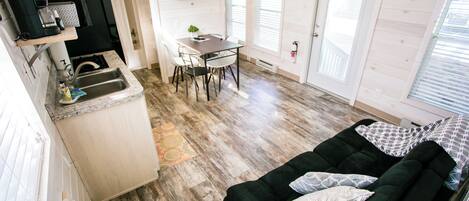 Un espacio habitable compacto con kitchenette, zona de comedor y área de estar con sofá.