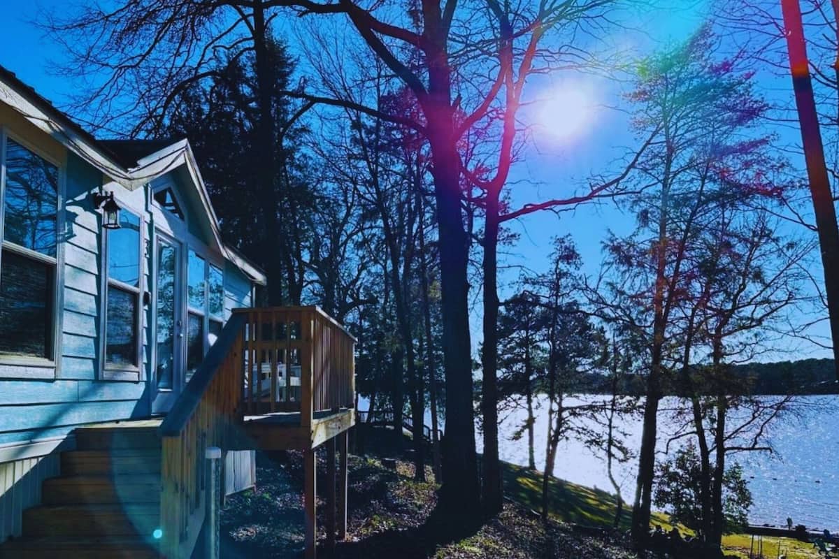 A house with a wooden deck and a view of a lake.