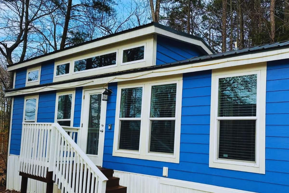 A two-story house with blue siding and white trim, featuring a front porch with steps and a railing.
