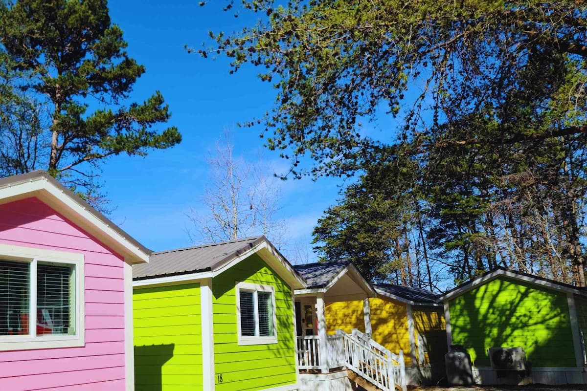 A row of colorful cabins with a clear sky and trees in the background.