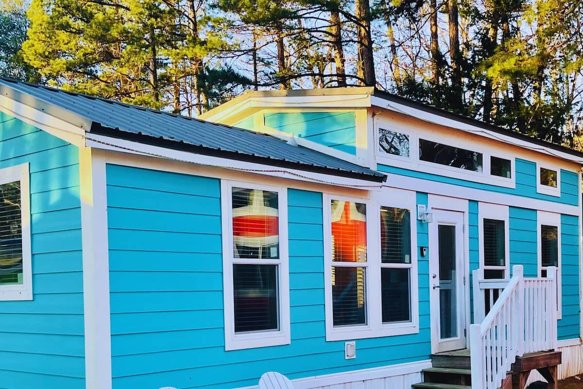 A turquoise house with white trim, a front porch, and a chimney.