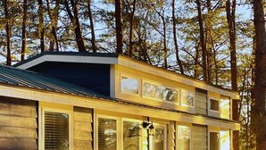 A cabin with a wooden exterior, a covered porch, and a staircase leading to the entrance. - Long Cove Resort near Charlotte Airport (Charlotte)