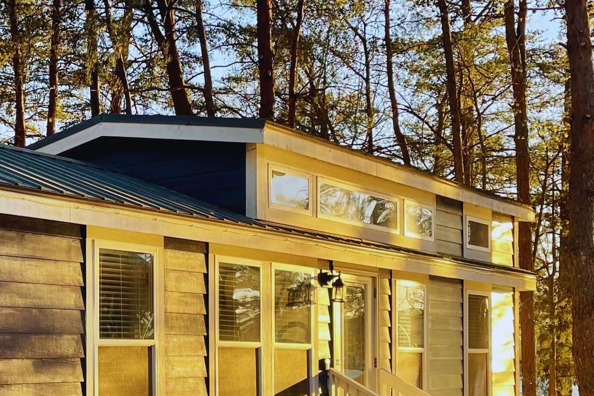 A cabin with a wooden exterior, a covered porch, and a staircase leading to the entrance.