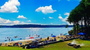 A beach with people swimming, sunbathing, and boats on the water. - Long Cove Resort near Charlotte Airport (Charlotte)