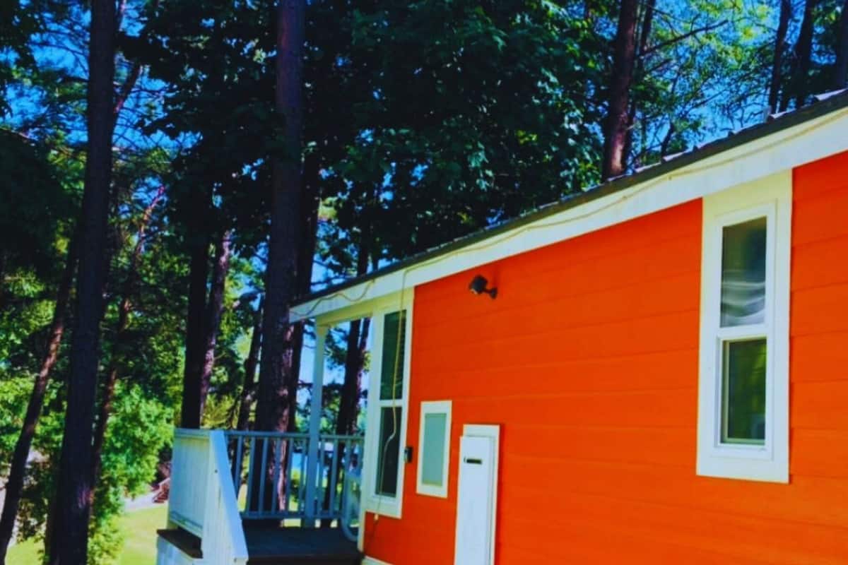 A bright orange cabin with a porch and a small window.