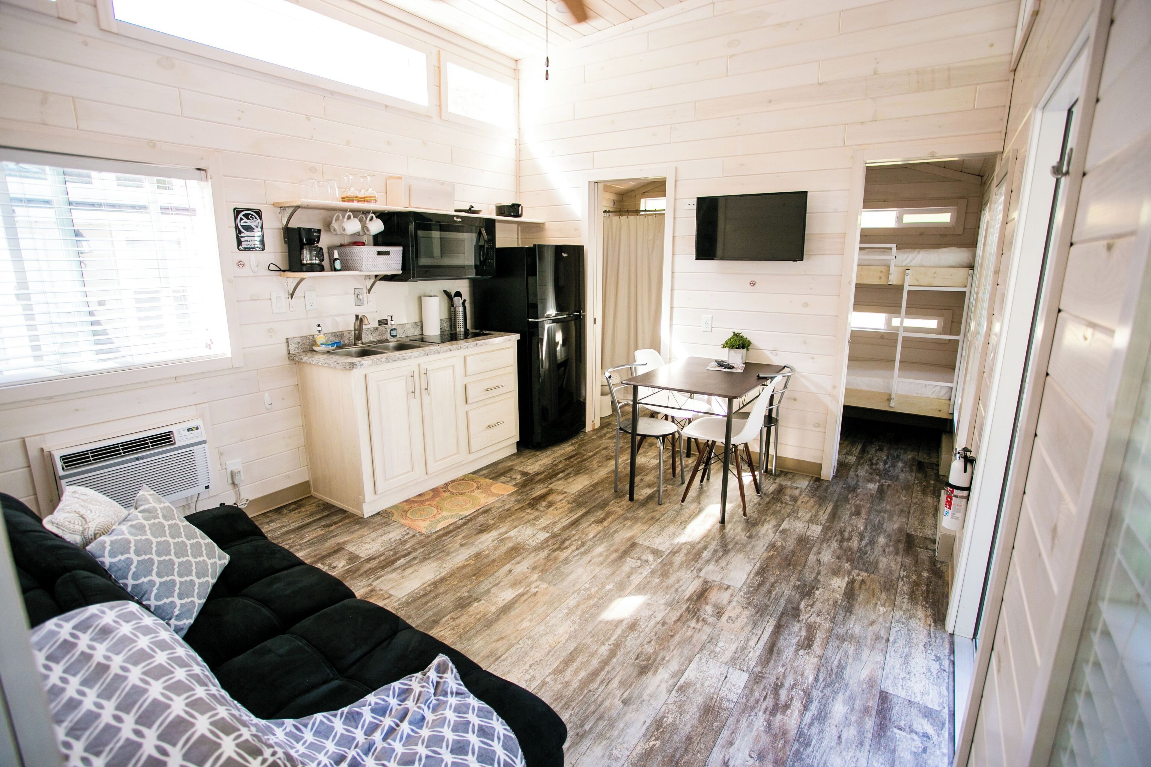 A compact kitchen with white cabinets, a black refrigerator, and a dining area with a table and chairs.