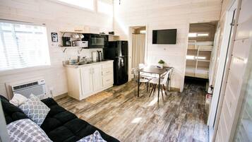 A compact kitchen with white cabinets, a black refrigerator, and a dining area with a table and chairs.
