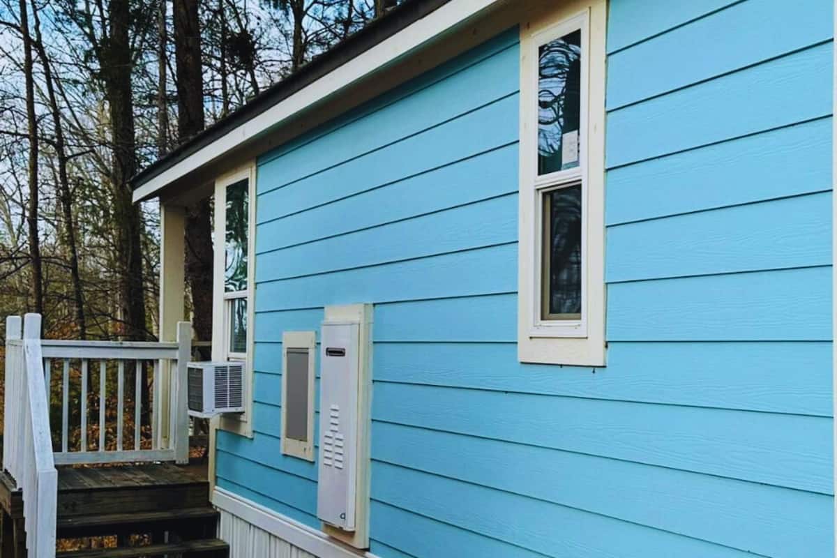 A blue house with a white porch and a small window.