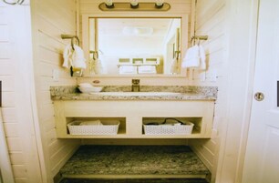 Un baño con encimera de granito, un lavamanos y dos cestas blancas.