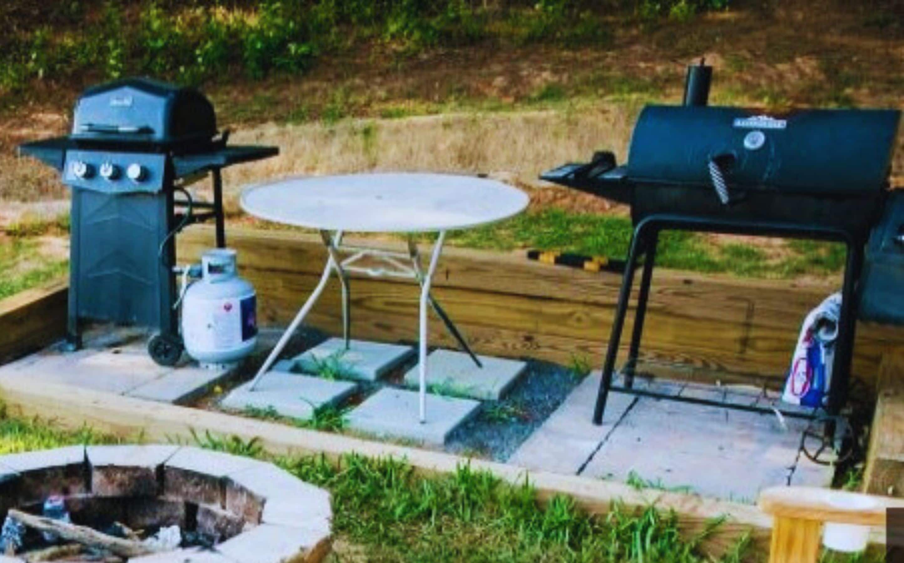 An outdoor barbecue setup with a grill, a table, and a gas cylinder.