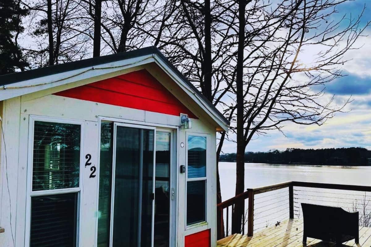 A small cabin with a red roof and a number '22' on the door, overlooking a body of water.