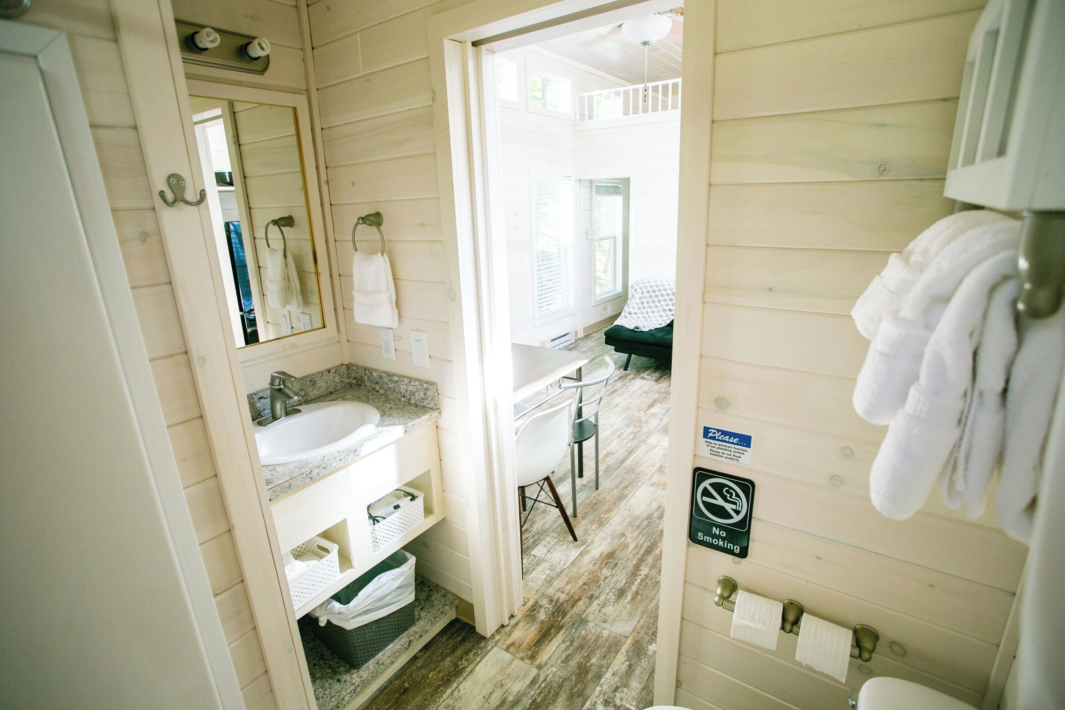 A wooden cabin bathroom with a sink, mirror, and towel rack.