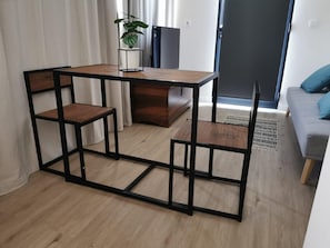 Ein kleiner, moderner Wohnraum mit einem Couchtisch aus Holz, zwei Sesseln, einer Zimmerpflanze und einem Sofa.