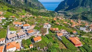 A coastal village with terraced houses, a clear view of the sea, and lush green hills. - Basalt Dwelling I by Homie (São Vicente)
