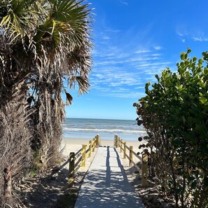A wooden pathway leading to a beach with a clear view of the ocean.